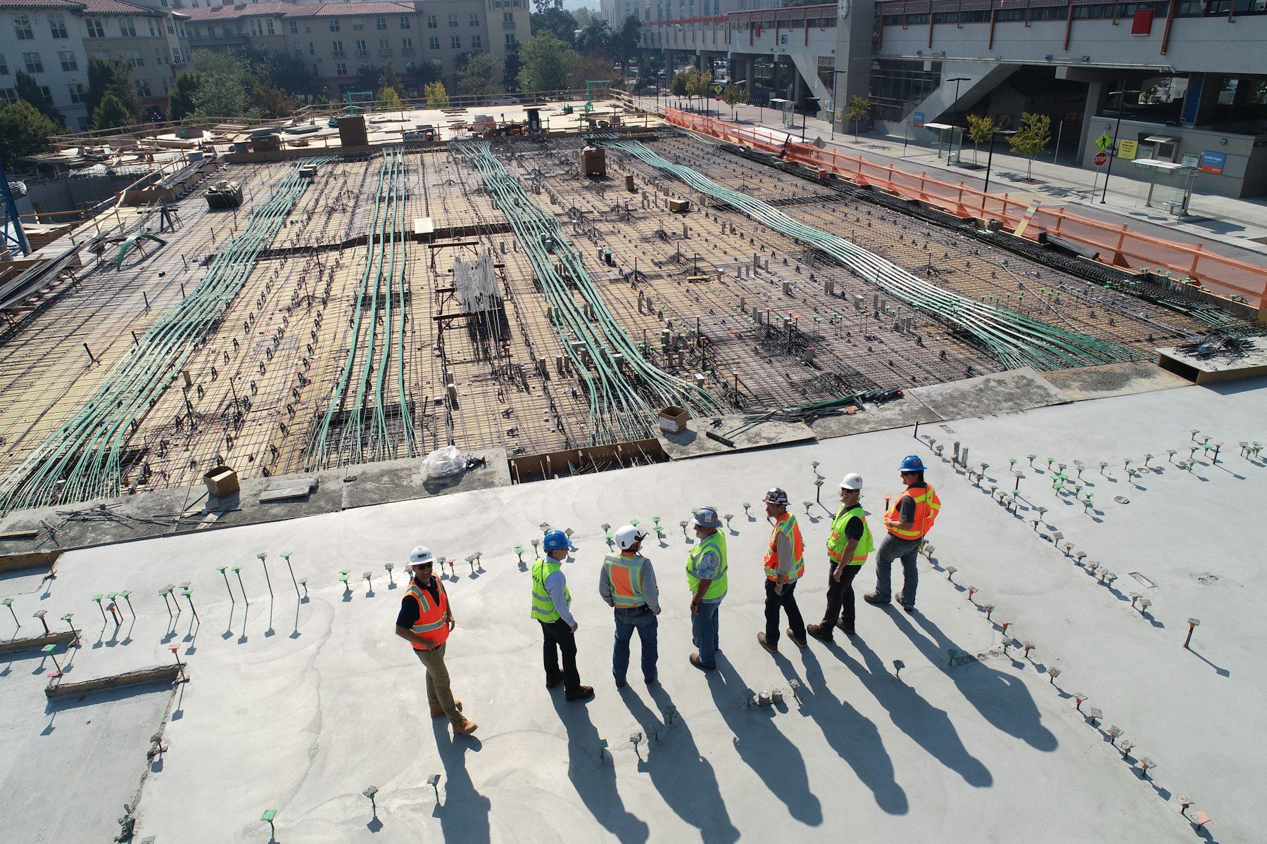 A team of engineers in hard hats and safety vests on a large construction site