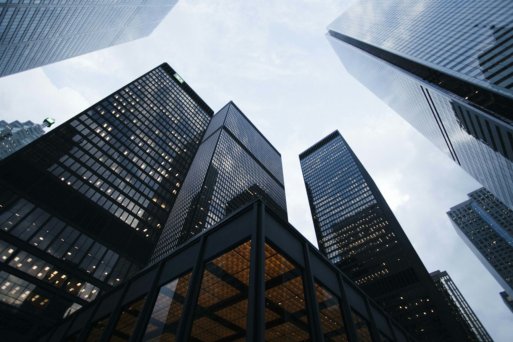 Glass towers seen from below against a pale sky