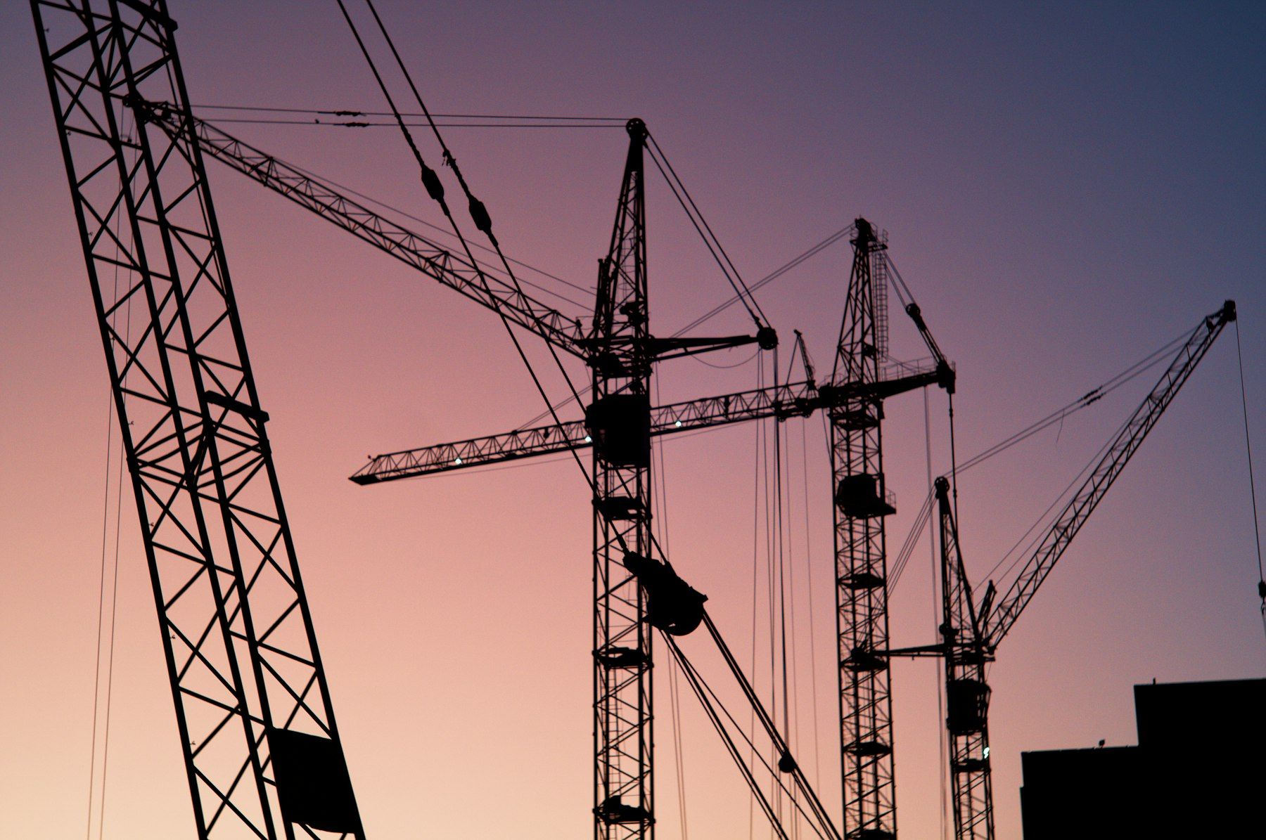 Tower cranes silhouetted against a dusk sky